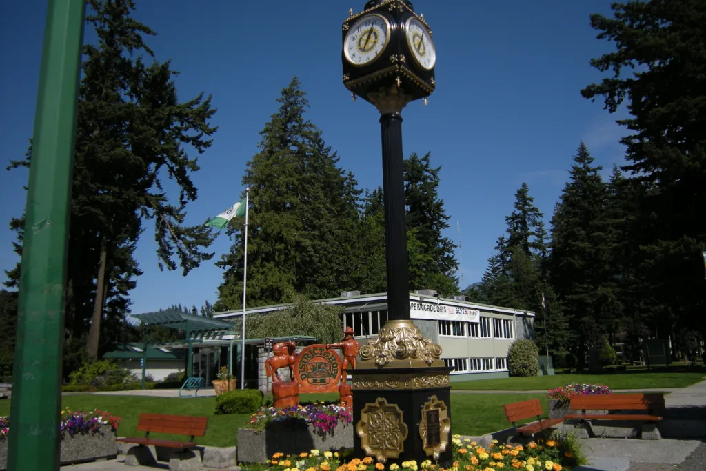 Clock and flower garden in a park in Hope, BC with evergreen trees