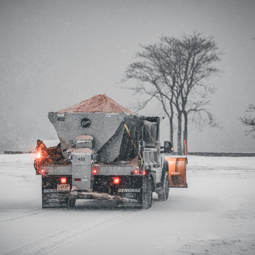 Salt spreader truck working on a snow-covered lot